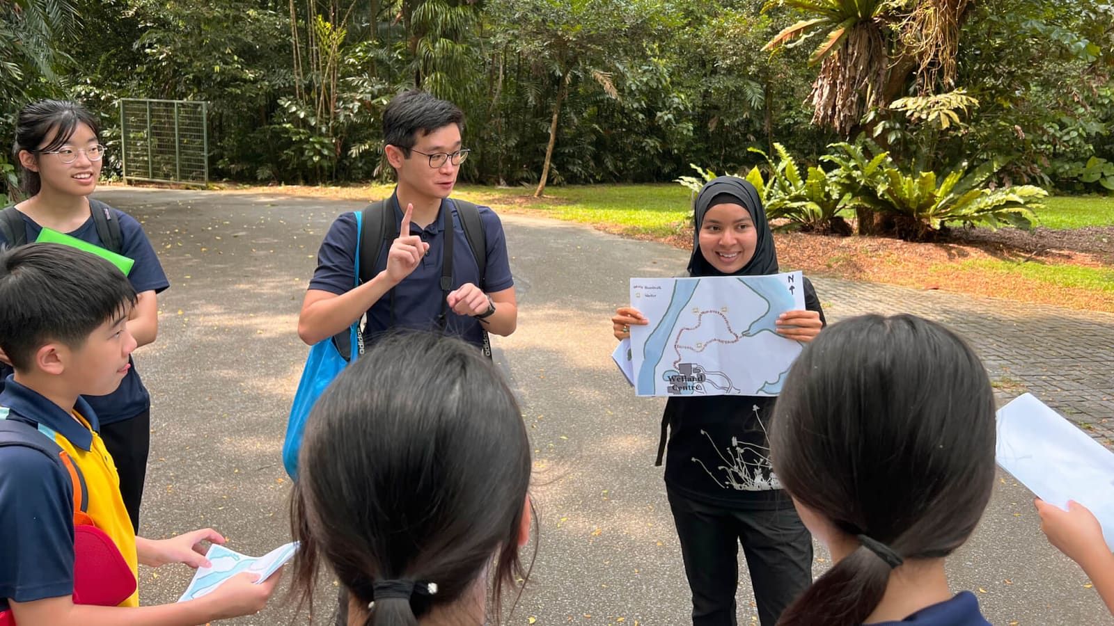 A student guide presenting a trail map to fellow students outdoors